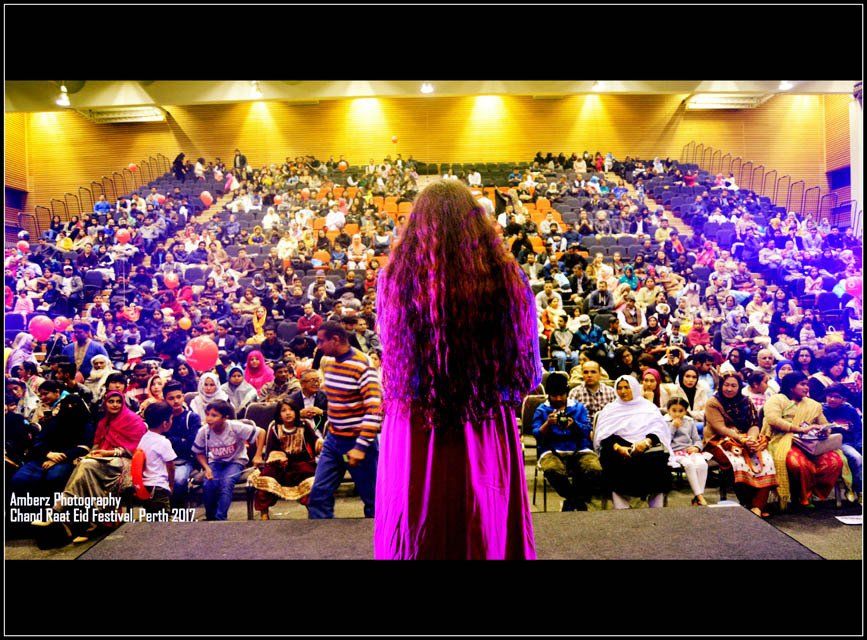 A woman in a purple dress is standing in front of a crowd