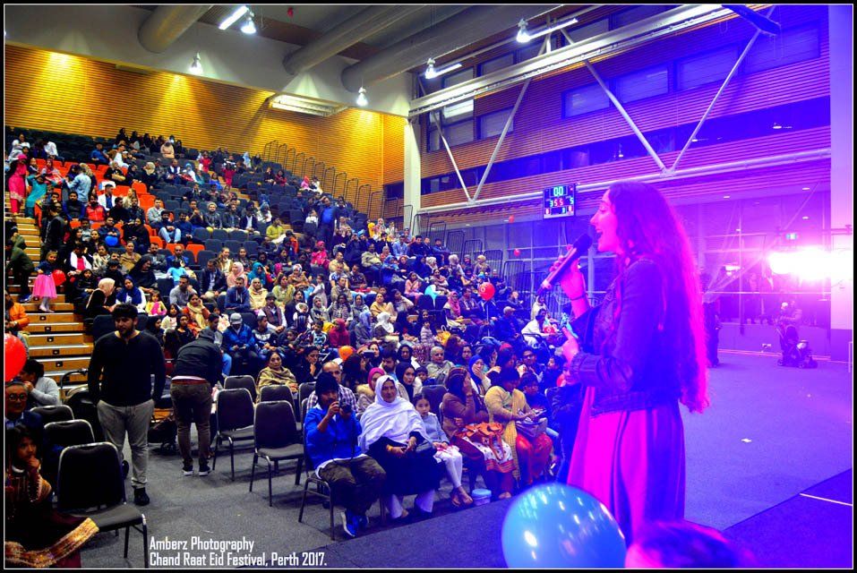 A woman singing into a microphone in front of a crowd