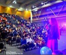 A woman is standing on a stage in front of a crowd of people.