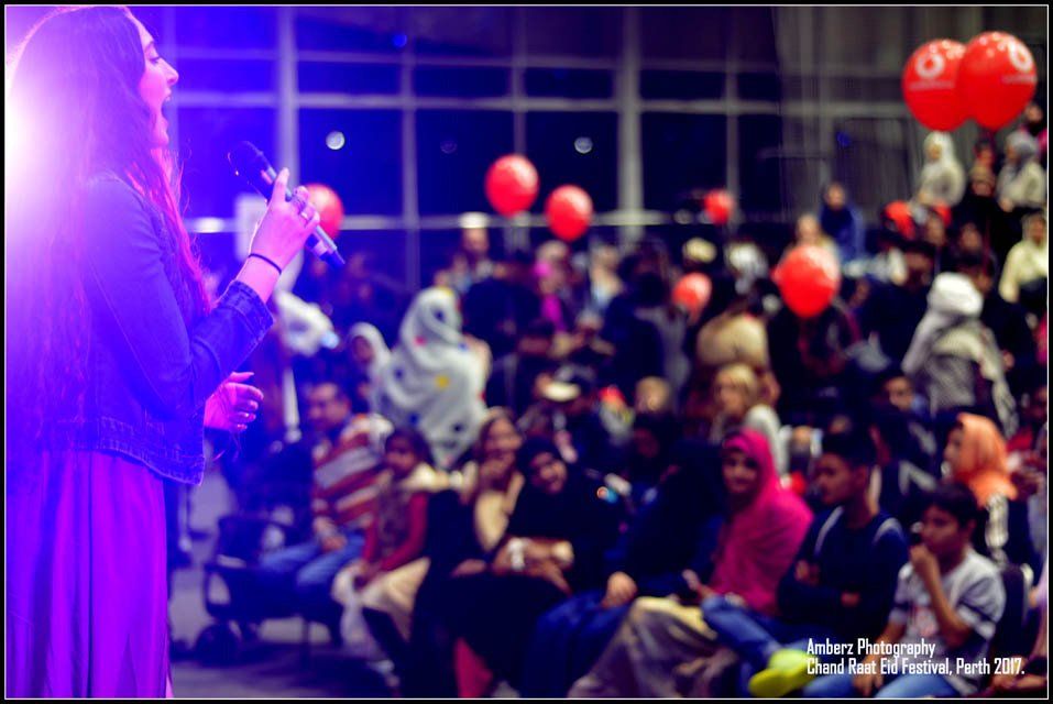 A woman singing into a microphone in front of a crowd