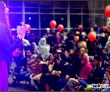 A woman is singing into a microphone in front of a crowd.