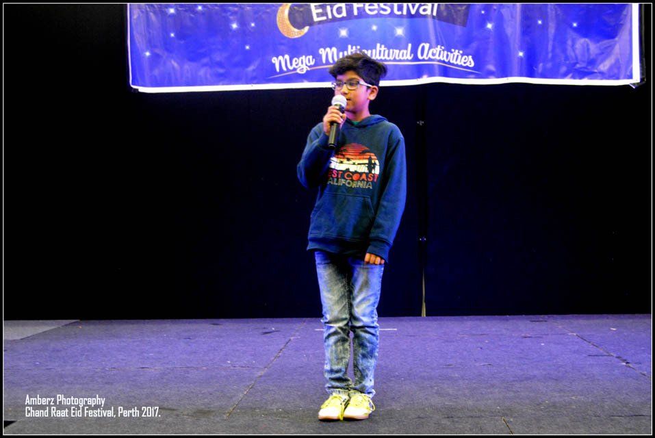 A young boy is singing into a microphone on a stage.