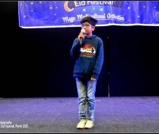 A young boy is standing on a stage holding a microphone.
