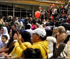 A crowd of people are sitting in a stadium with balloons.
