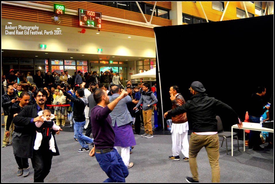 A group of people are dancing in a room with a sign that says ' lucas photography ' on it