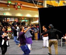 A group of people are dancing in front of a sign that says festival park