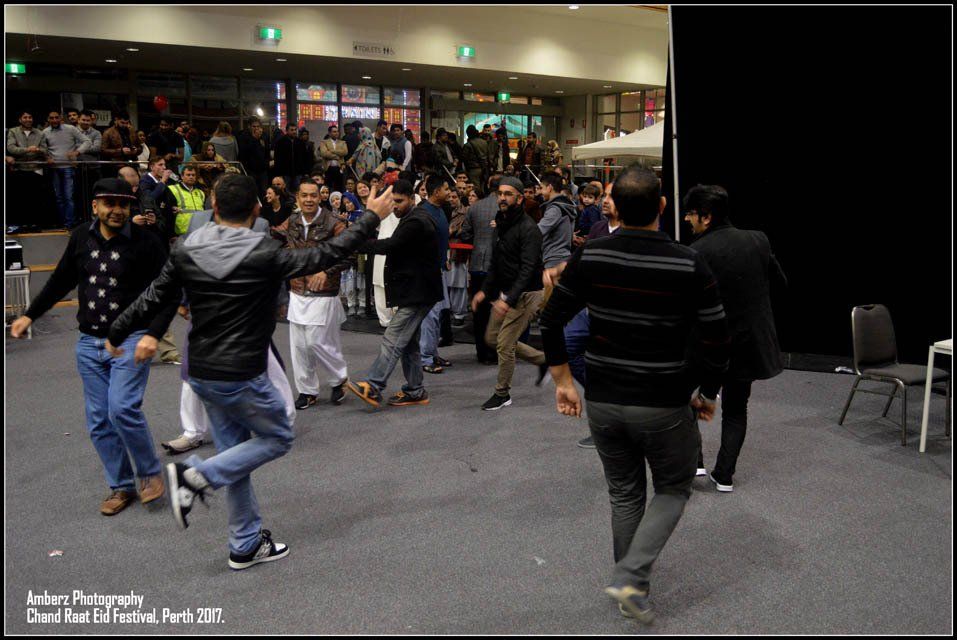 A group of men are dancing in a room with a sign that says photography