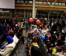 A large group of people are sitting in chairs in front of a large screen.