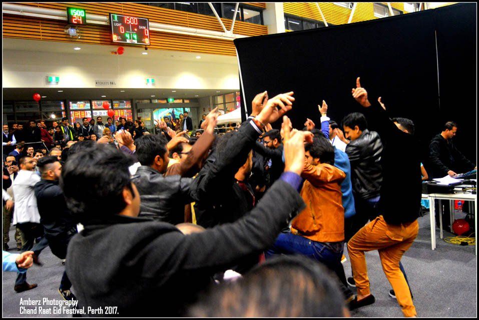 A group of people are dancing in front of a black curtain