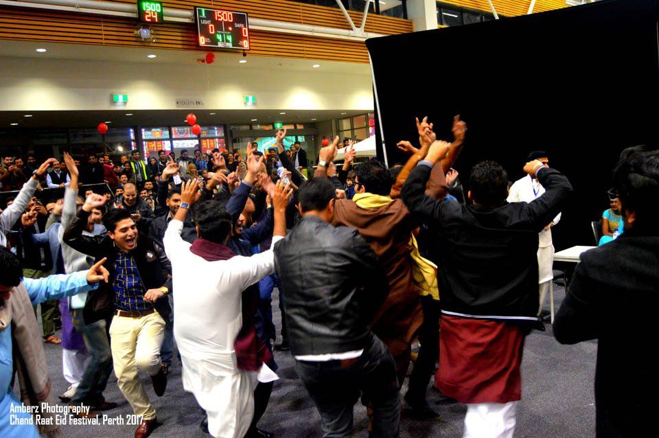A group of people are dancing with their hands in the air