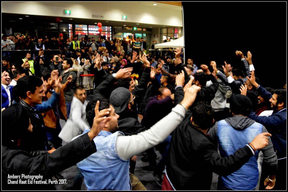 A group of people are dancing in a circle with their hands in the air