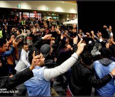 A large group of people are standing in a circle with their hands in the air.