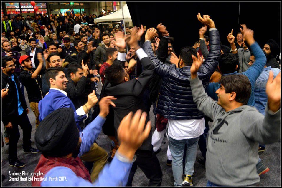 A group of men are dancing in a crowd with their hands in the air