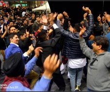 A large group of people are dancing in a crowd with their hands in the air.
