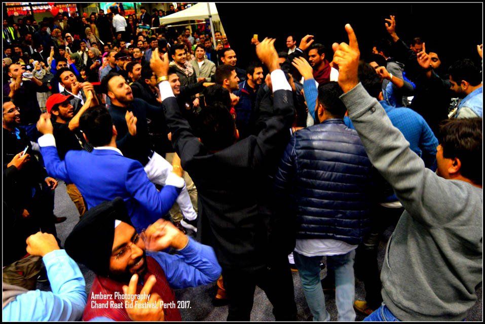 A crowd of people are dancing with their hands in the air