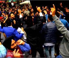 A group of people are dancing in a crowd with their hands in the air.