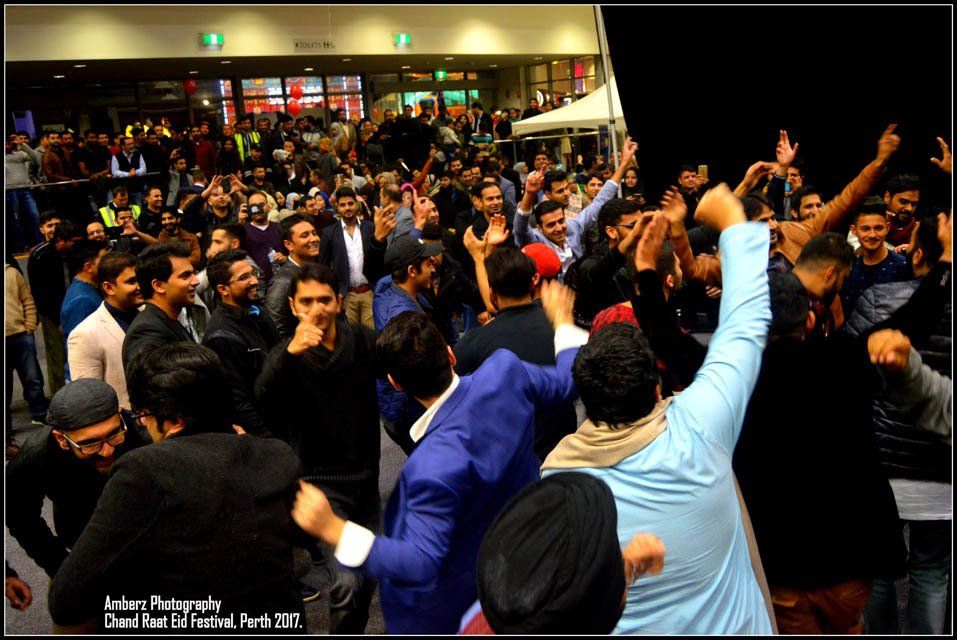A crowd of people are dancing in front of a building