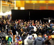 A large group of people are standing in front of a stage.