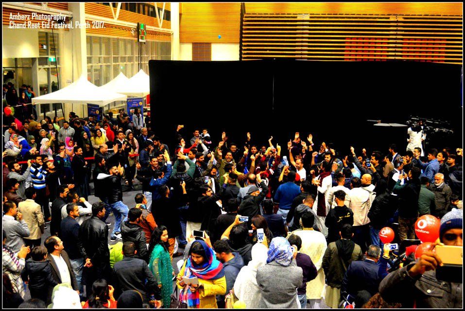 A large crowd of people are gathered in front of a stage.