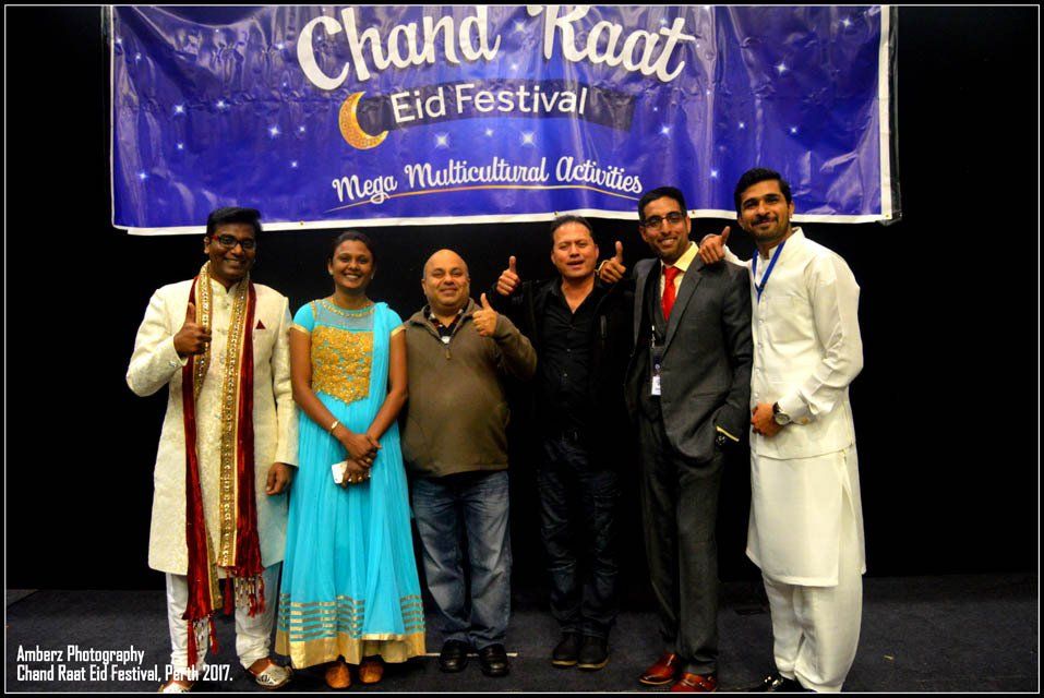 A group of people standing in front of a banner that says chand raat