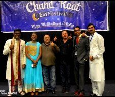 A group of people are posing for a picture in front of a banner that says chand raat eid festival.