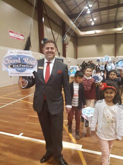 A man in a suit and tie is holding a sign that says chand road