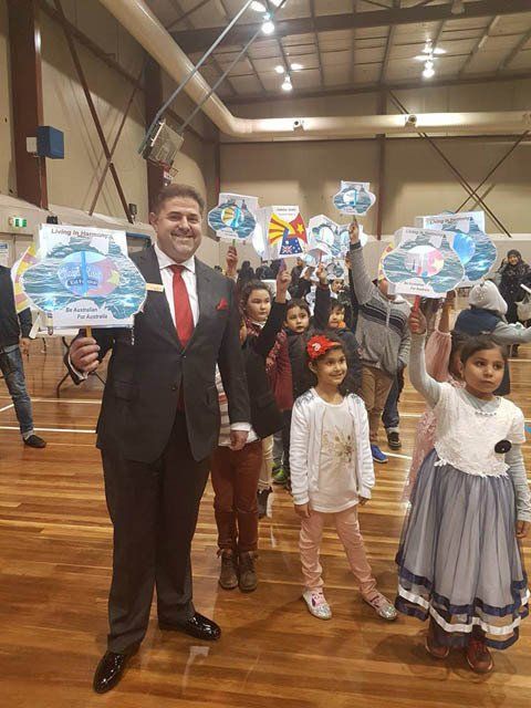 A man in a suit and tie is standing next to a group of children holding up signs.