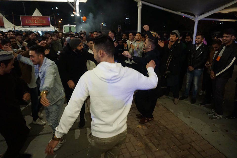A man in a white hoodie is dancing in front of a crowd of people.