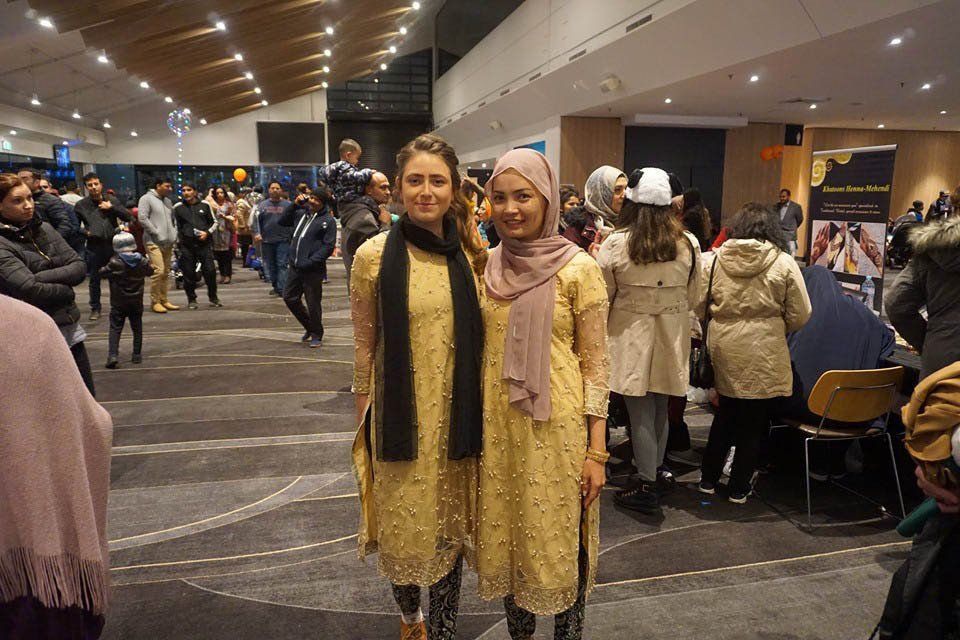 Two women are standing next to each other in a crowded room.