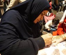 A woman in a hijab is getting a tattoo on her hand.