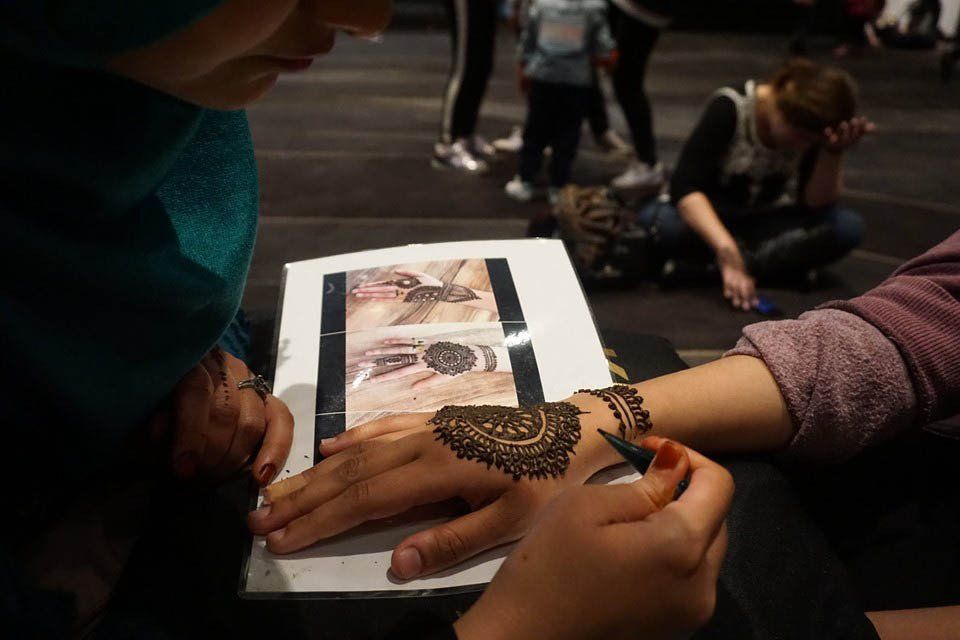 A woman is getting a henna tattoo on her hand.