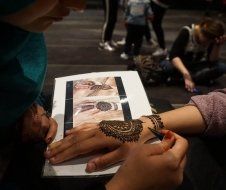 A woman is getting a henna tattoo on her hand.