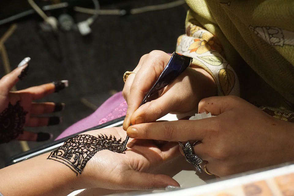 A woman is getting a henna tattoo on her wrist