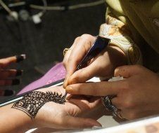 A woman is getting a henna tattoo on her hand.