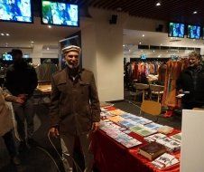 A man is standing in front of a table with books on it.
