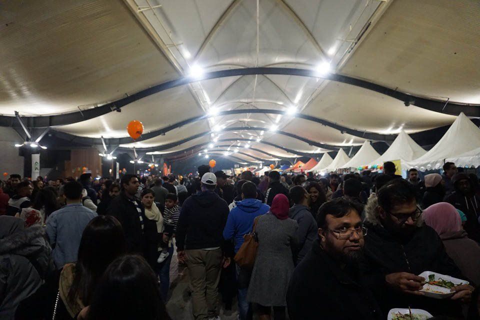 A crowd of people are gathered under a tent at a festival.