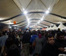 A crowd of people are gathered under a tent at a festival.
