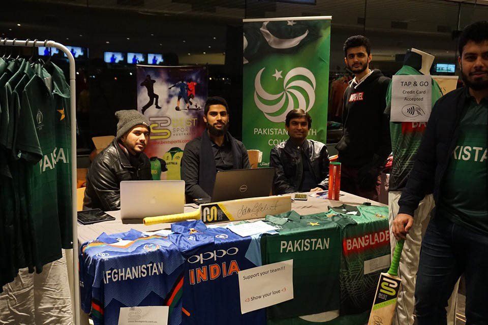 A group of men are standing around a table that says pakistan on it