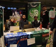 A group of men are sitting at a table with laptops.