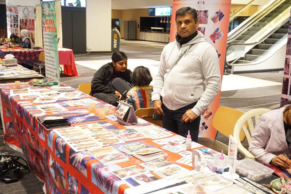 A man is standing in front of a table with a lot of papers on it.