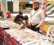 A man is standing in front of a table with papers on it.