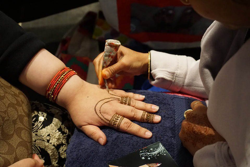 A woman is getting a henna tattoo on her hand