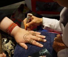 A woman is getting a henna tattoo on her hand.