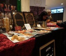 A woman is sitting at a table with a sign that says henna on it.