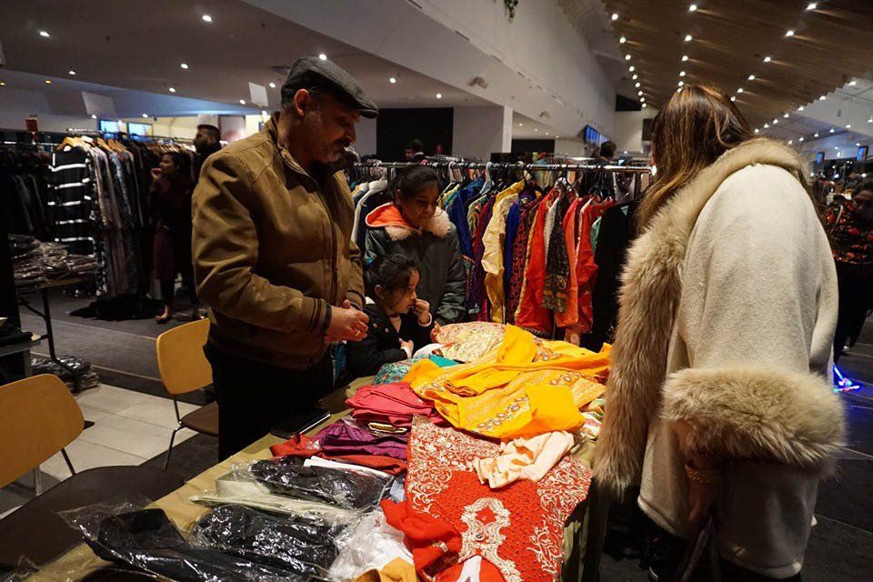 A man and a woman are looking at clothes at a clothing store.