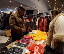 A man is standing at a table in a store looking at clothes.