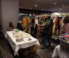 A group of people are standing around a table in a room looking at clothes.