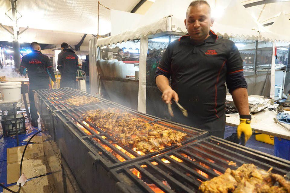A man is cooking meat on a large grill.