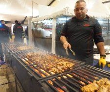 A man is cooking food on a grill in a tent.