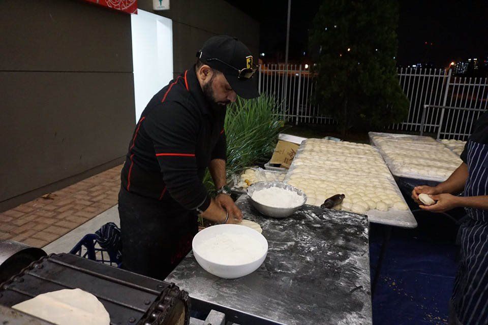 A man is preparing food in bowls on a table.